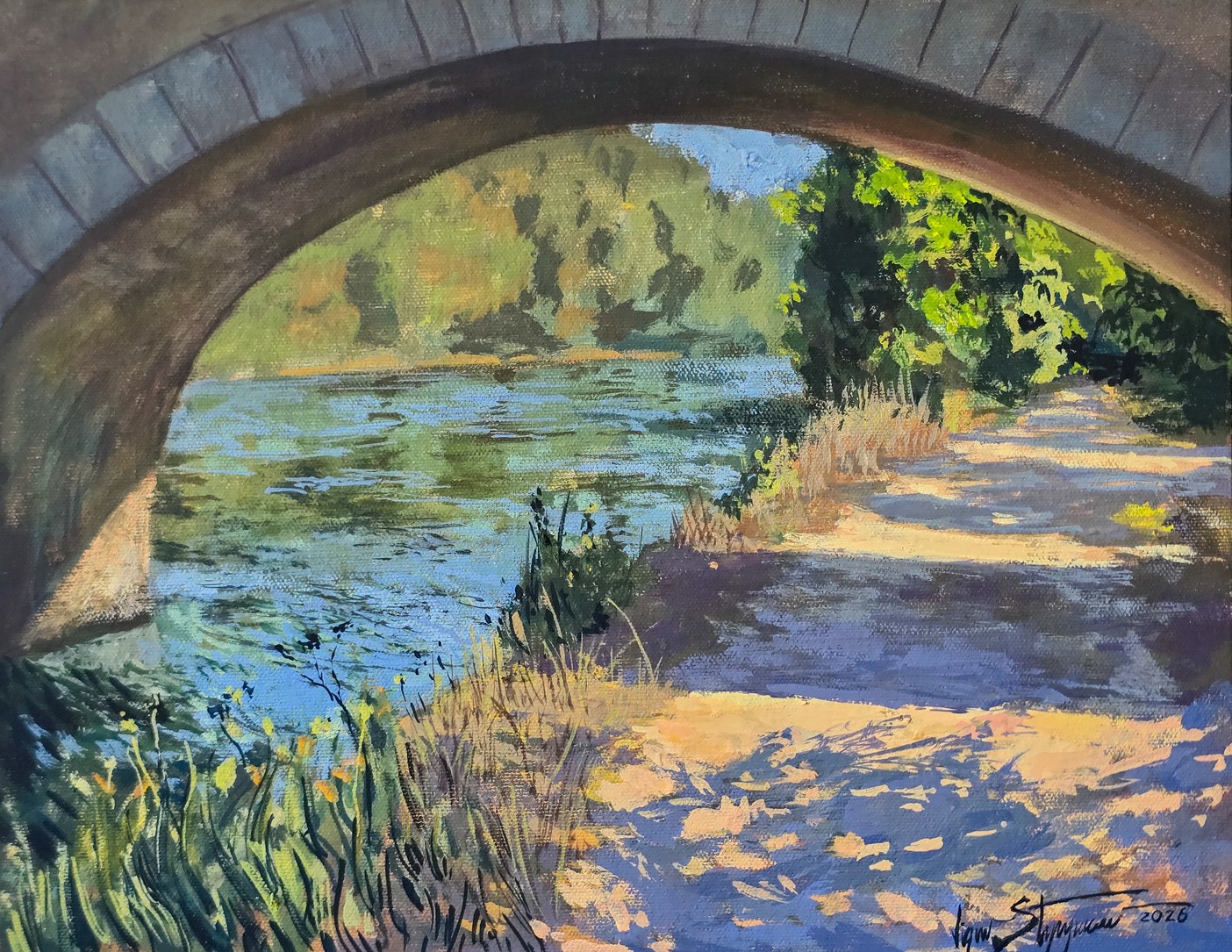 Sendero junto al río bajo un puente